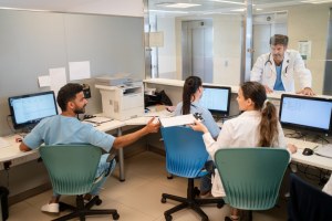 Administrative staff woking at hospital office with doctor standing at front desk